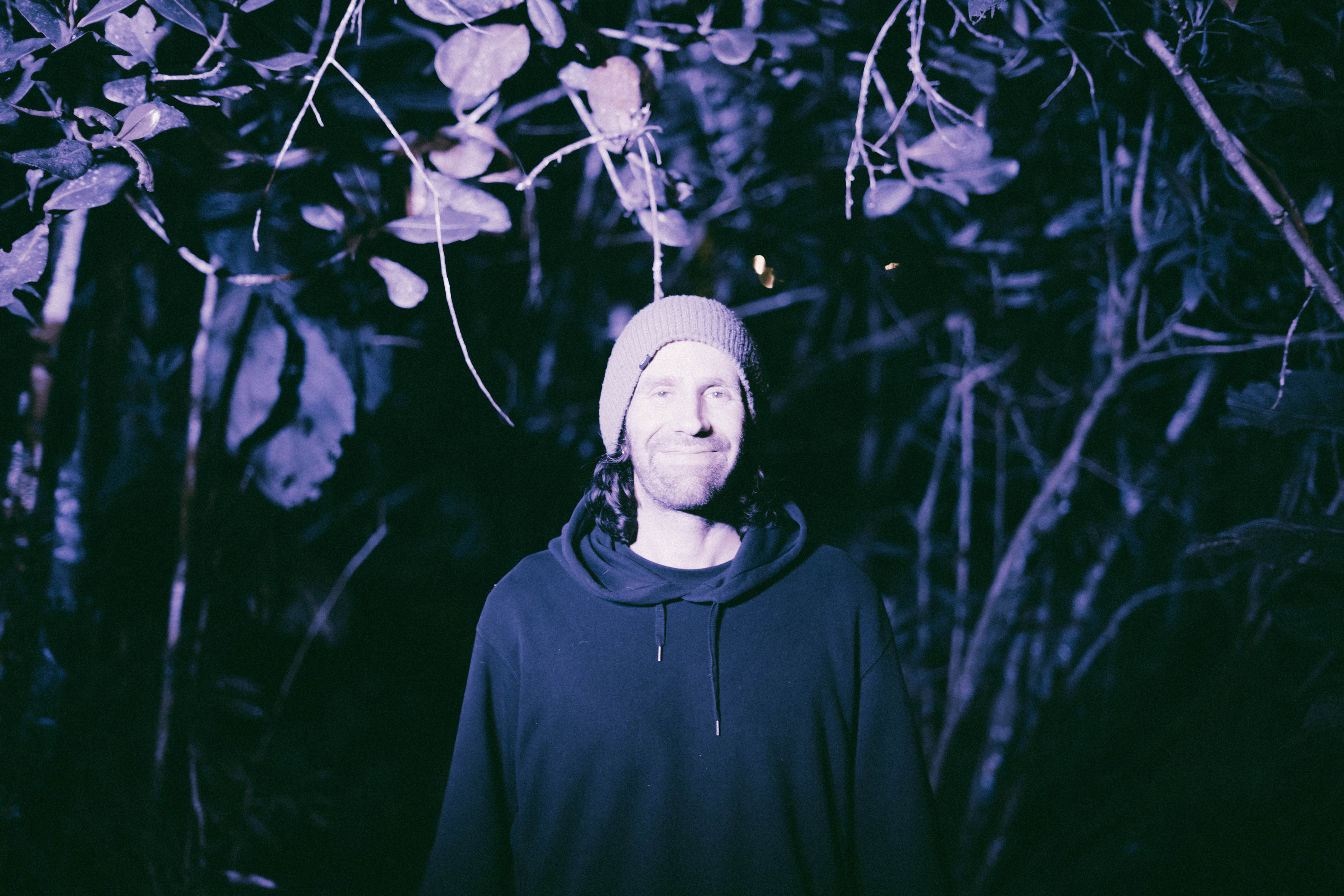 magenta stands and smiles in the middle of forest bathed in light